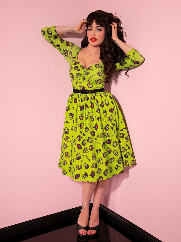 Micheline Pitt running her fingers through her hair while showing off the Wicked Swing Dress in Vintage Monster Mash Print. 