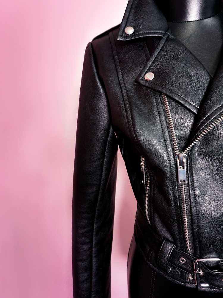 Close-up product shot of the intricate stitching and zipper craftsmanship on the Bad Girl Cropped Motorcycle Jacket in Vegan Leather.