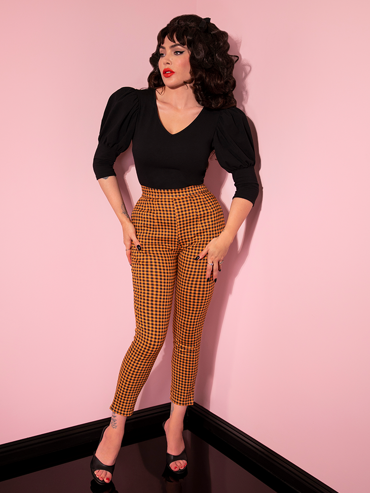 Full length shot of Micheline Pitt in the Cigarette Pants in Orange Pumpkin Gingham with a flowy black top.