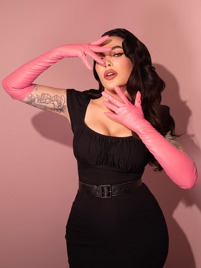 Micheline Pitt wearing the Faux Leather Opera Gloves in Flamingo Pink in an all black retro style outfit from Vixen Clothing.