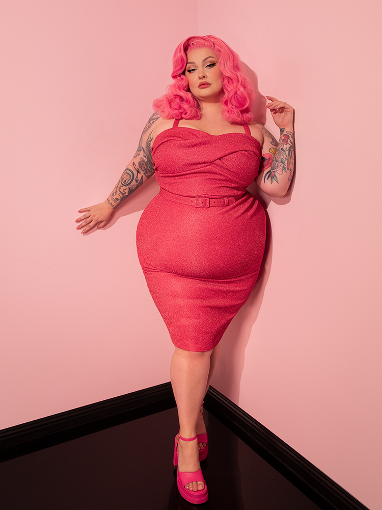 Radiating confidence and allure, the female model confidently shows off the Jawbreaker Wiggle Dress in Candy Pink Lurex by Vixen Clothing, a perfect embodiment of the brand's retro clothing aesthetic.