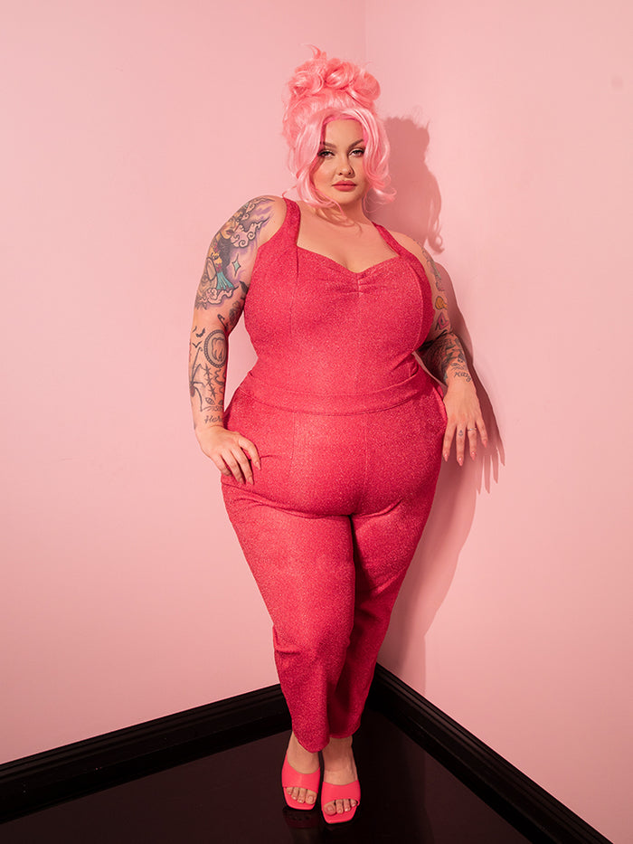 Exuding beauty and retro charm, the stunning model proudly showcases the Candy Pink Lurex Cigarette Pants from Vixen Clothing, embodying vintage style.