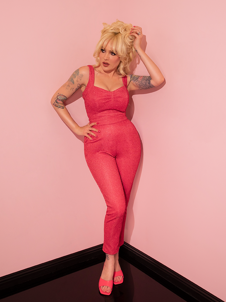 The Candy Pink Lurex Cigarette Pants from Vixen Clothing take center stage as the gorgeous retro style model confidently flaunts them, epitomizing the essence of vintage fashion.