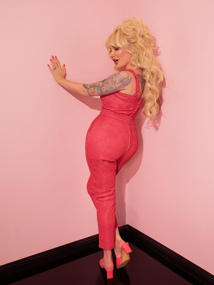 Gracefully donning the Candy Pink Lurex Cigarette Pants from Vixen Clothing, the stunning retro style model captivates with her timeless beauty.