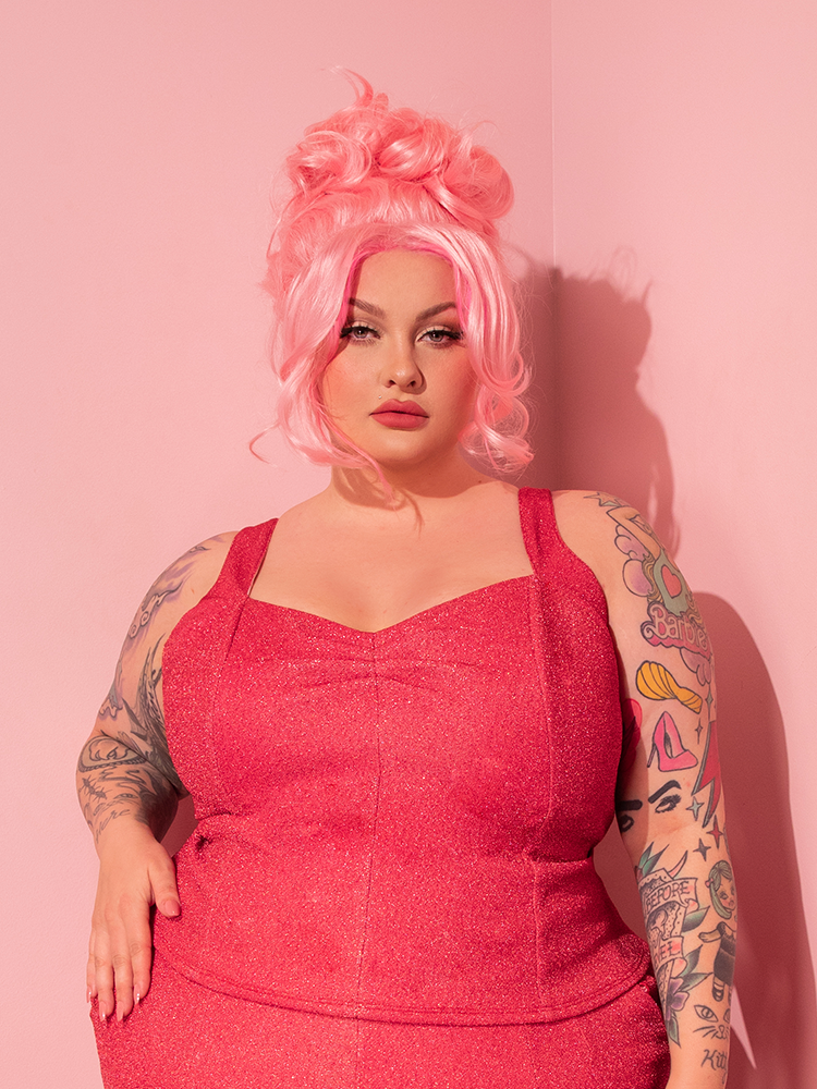 With an enchanting allure, the stunning model showcases her retro attire, with the spotlight on the Candy Pink Lurex Vamp Top by Vixen Clothing.