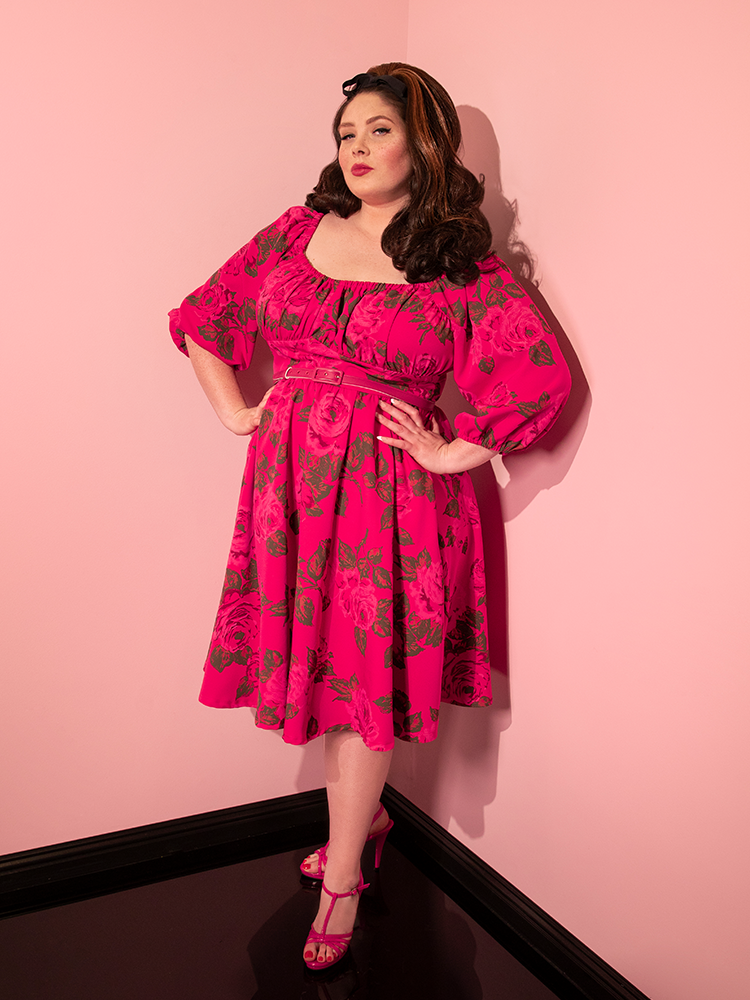 Model turned to the side the show off the Vacation Dress in Hot Pink with Pink Roses from Vixen Clothing.