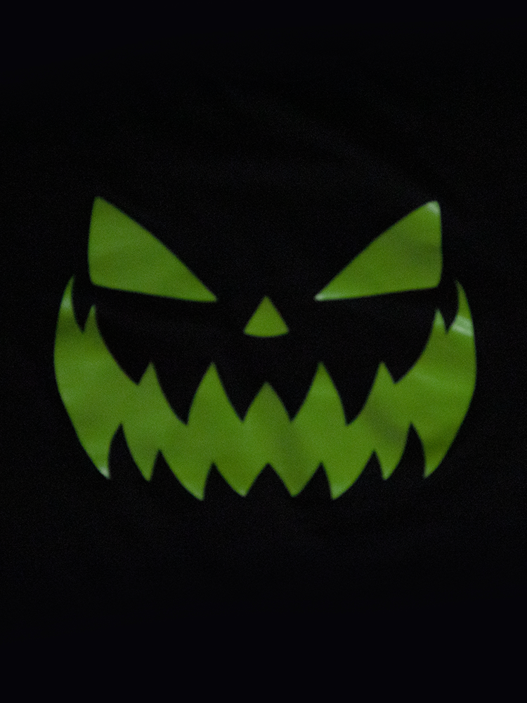 Close-up shot of the jack-o-lantern print of the shirt glowing in the dark.