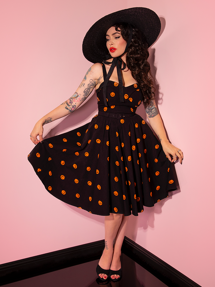 Micheline Pitt pulls out on the sides of the skirt of the Pumpkin King Maneater Swing Dress in Black.