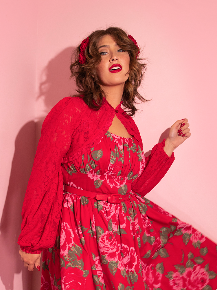 Francesca twirls in a bright red rose print dress while showcasing the Vixen Vintage Lace Bolero in Classic Red over the top.