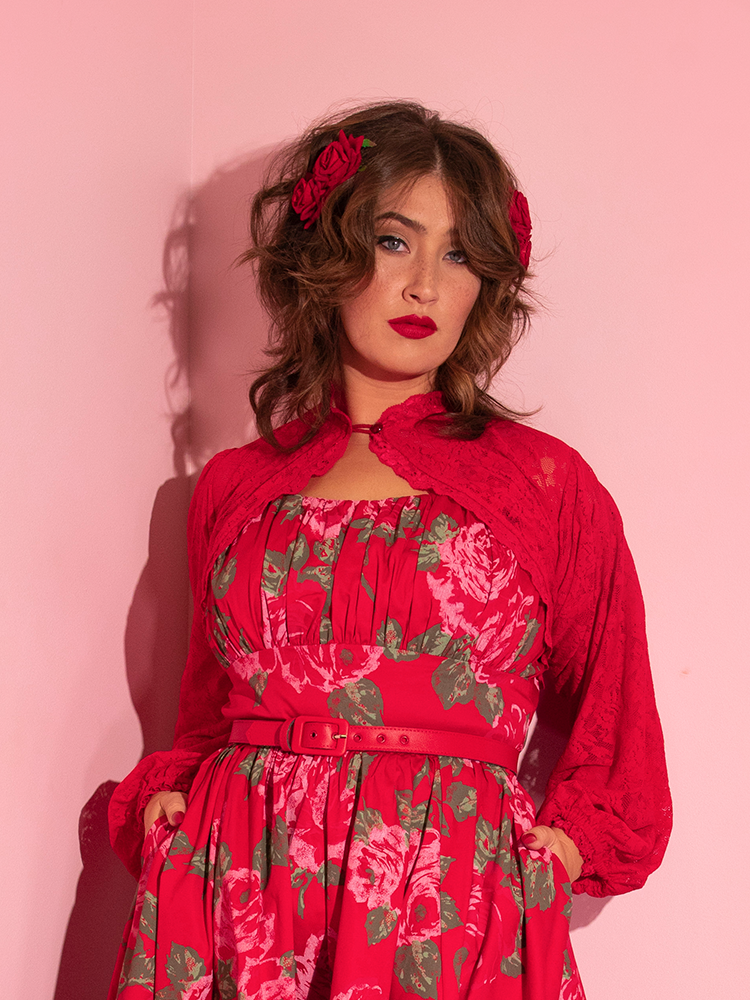 Francesca flashes a mysterious look into the camera while tucking her hands into the pockets of the red retro inspired dress she's wearing combined with a ravishing Vixen Vintage Lace Bolero in Classic Red on top.