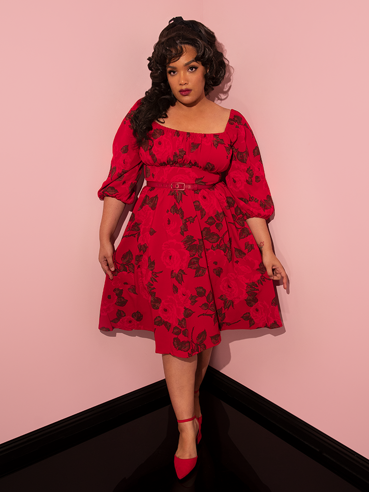Full length shot of Ashleeta wearing the Vacation Dress in Vintage Red Rose Print along with vibrant red shoes.