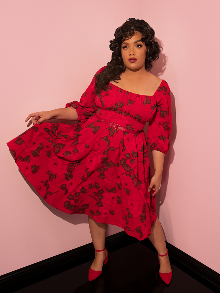 Ashleeta holds up a section of the skirt on the Vacation Dress in Vintage Red Rose Print to show off the gorgeous and vibrant color and print.