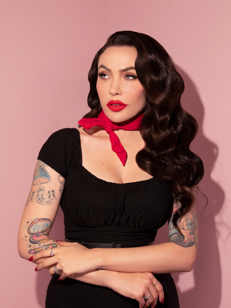 A portrait style shot of Micheline Pitt looking upwards while wearing the Vintage Bandana in Red from Vixen Clothing.