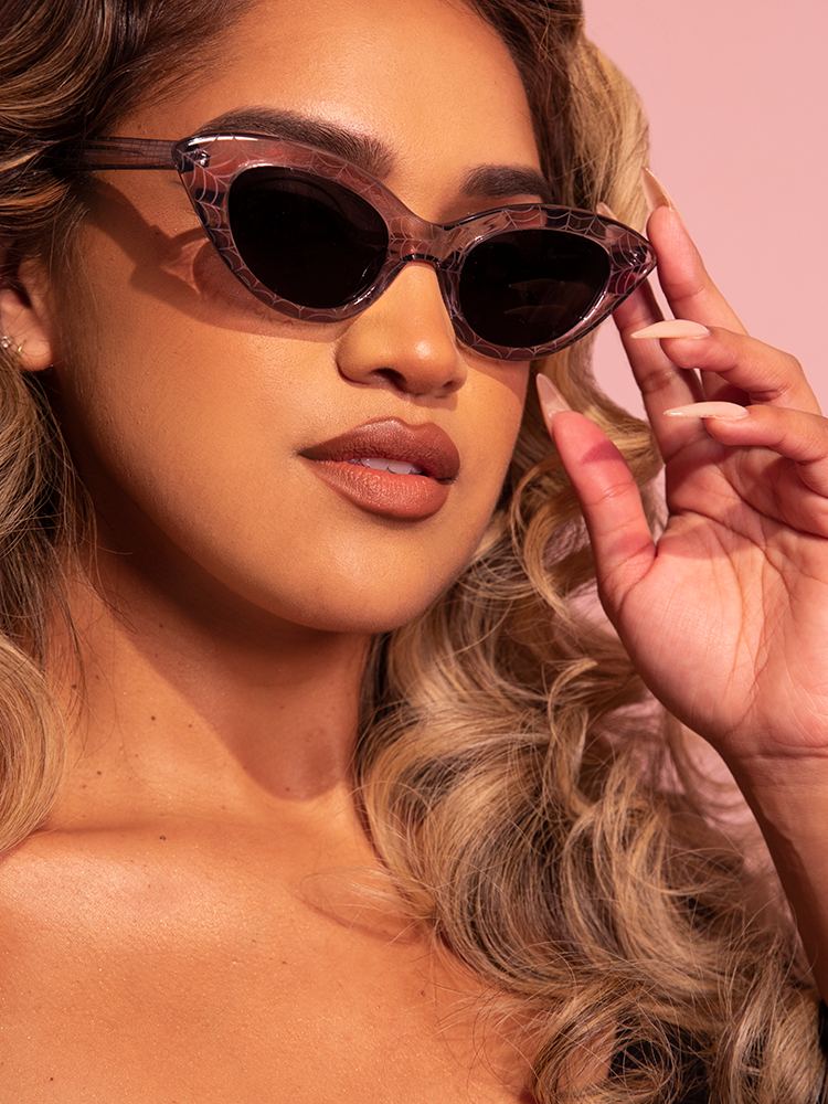 Close up of a female model sporting the Fashion Doll Cat Eye Sunglasses in Spider Web To complement her overall retro clothing outfit.