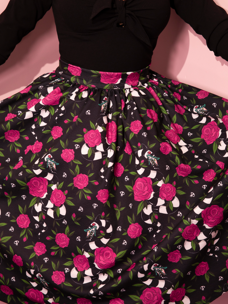 Close-up of the unique print on the retro style skirt a female model is showing off. - BEETLEJUICE™ Sandworm & Roses Swing Skirt