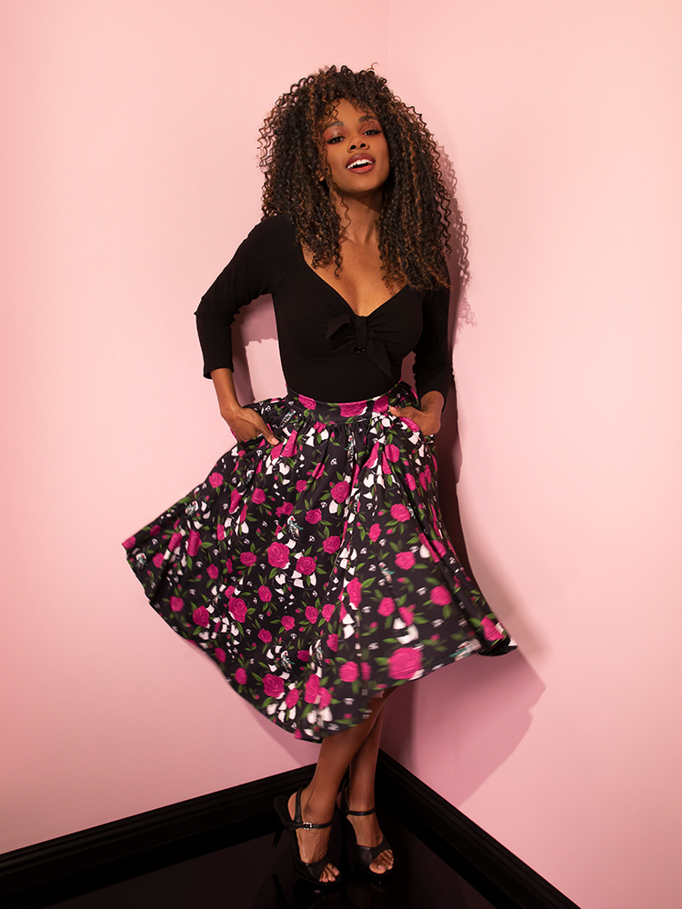 Model tucking her hands into the pockets of the BEETLEJUICE™ Sandworm & Roses Swing Skirt.