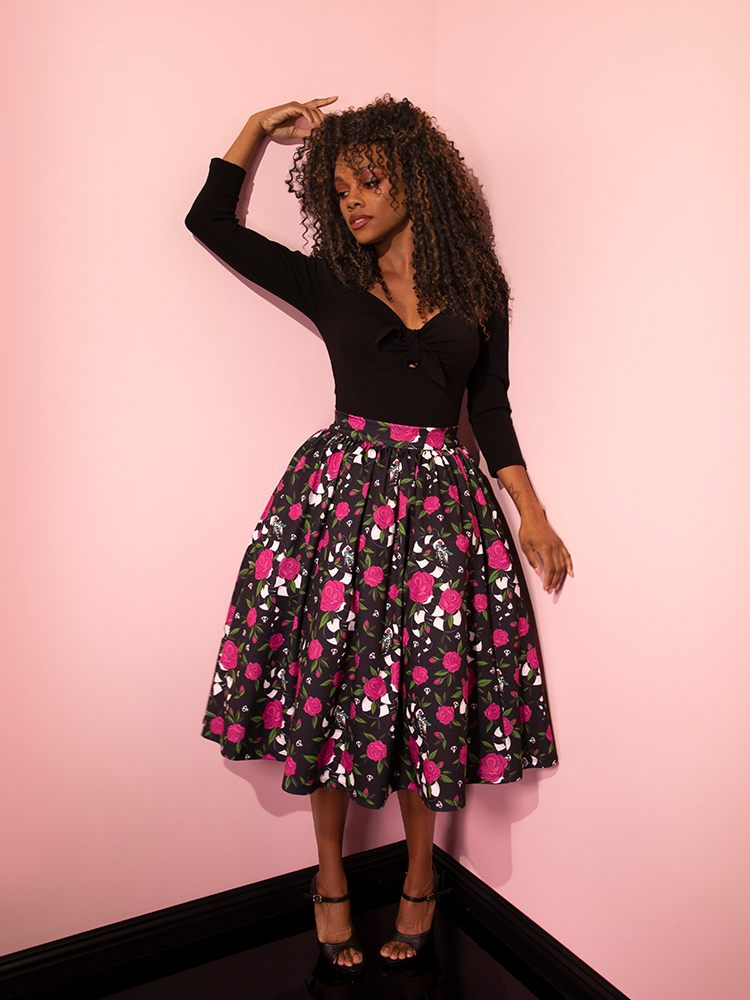 Model strikes a contemplative pose while looking off-camera while wearing the BEETLEJUICE™ Sandworm & Roses Swing Skirt.