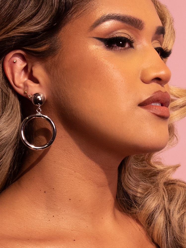 Latin model shot wearing the Bad Girl Hoop Earrings in Silver from retro dress brand Vixen Clothing.