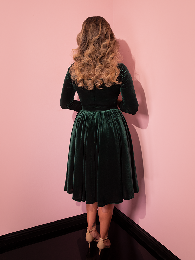 The back of the Starlet Swing Dress in Hunter Green Velvet being worn by female model.