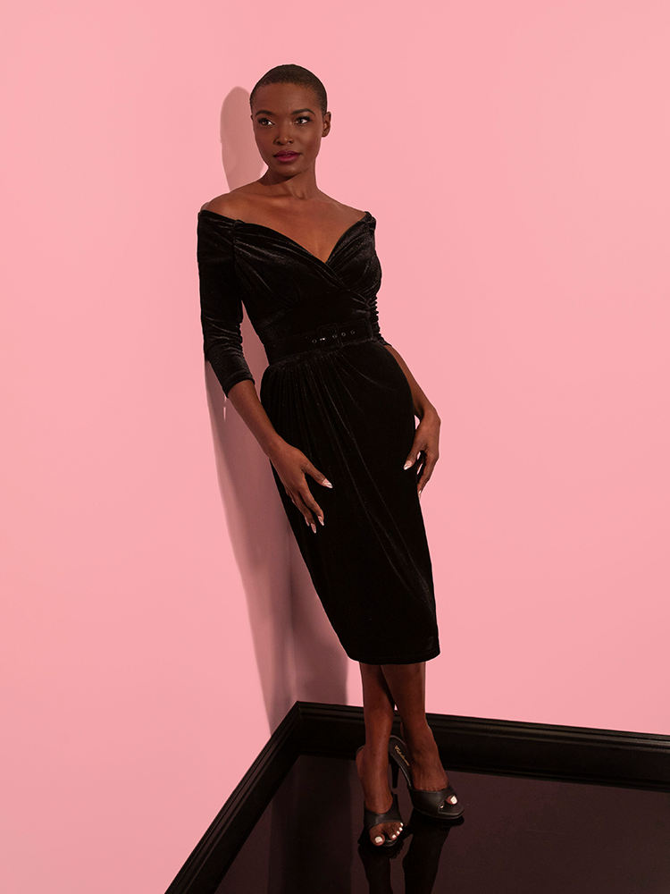 The Vixen Clothing brand's Starlet Wiggle Dress in Black Velvet is modeled beautifully by the female model, who flaunts it with style and grace.