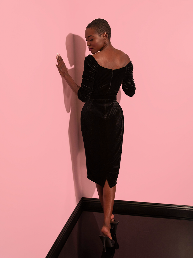 The Starlet Wiggle Dress in Black Velvet from Vixen Clothing is a perfect fit for the female model, who looks radiant and alluring.
