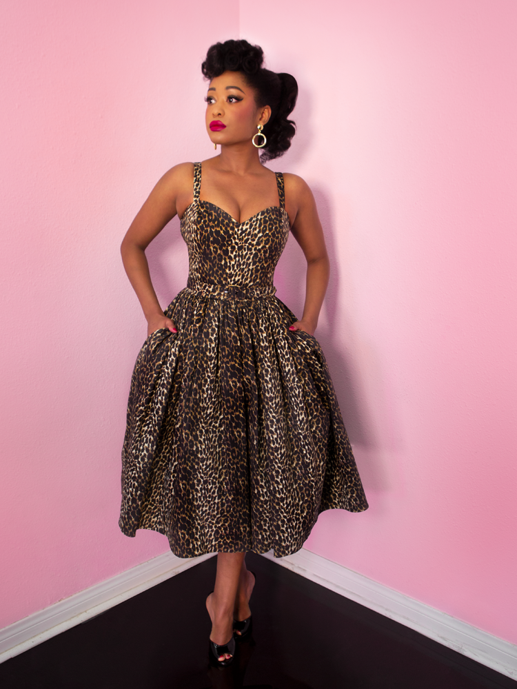 Model, looking off-camera with her hands in her pockets, wearing a vintage inspired leopard print dress.