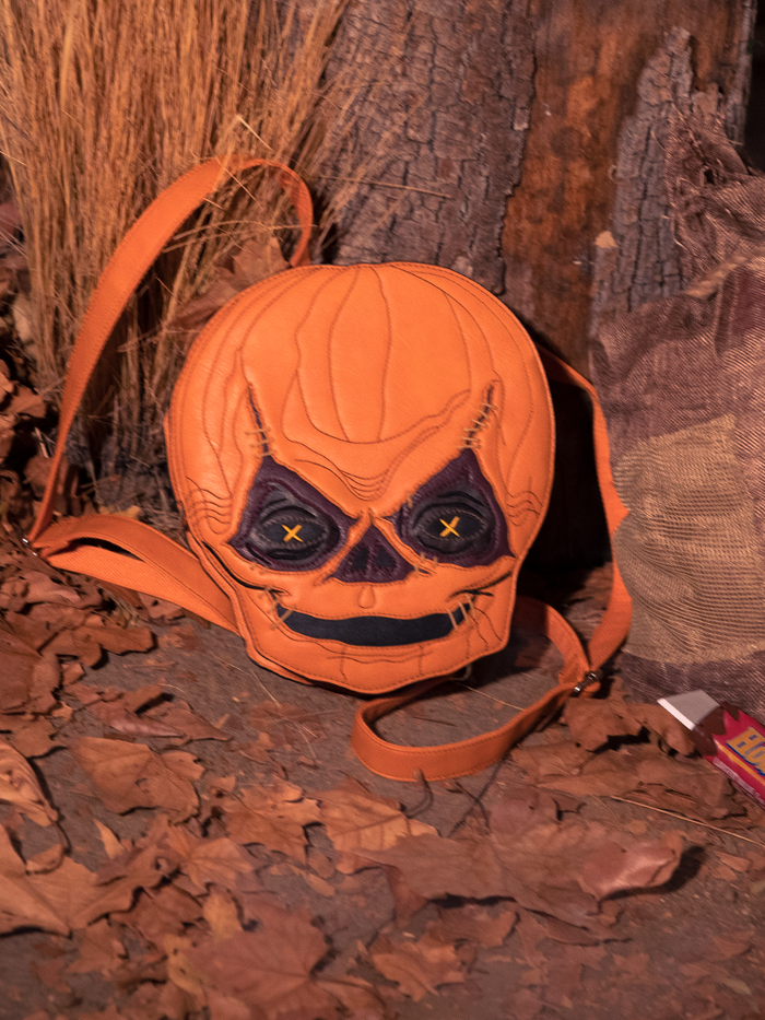 The TRICK R TREAT™ Sam Backpack sitting in front of an old tree and amongst dead leaves.