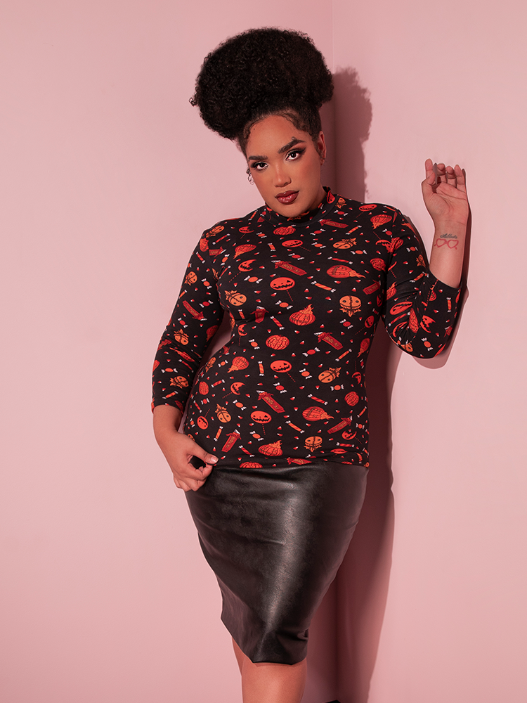 The TRICK R TREAT™ Bad Girl 3/4 Sleeve Top in Candy Corn Novelty Print being pulled gently down to show off the intricate design.