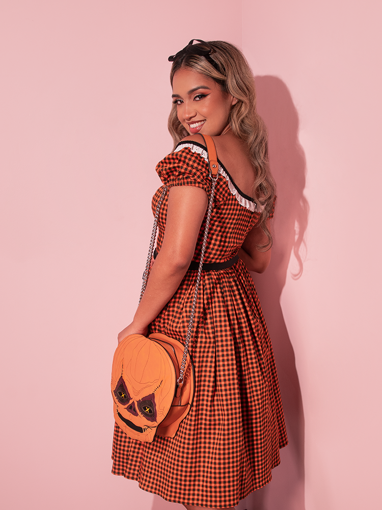 Model facing away from the camera to show off a back view of her retro style dress and teh TRICK R TREAT™ Sam Crossbody Bag.