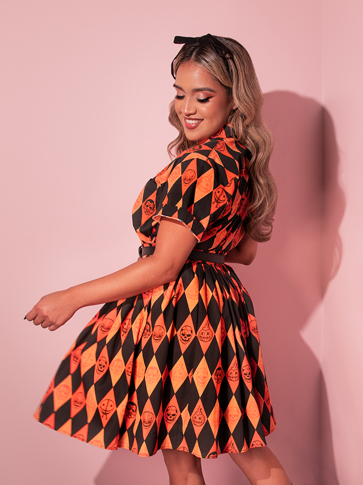 Model smiling and twirling around in the TRICK R TREAT™ Button Up Shirt in Halloween Harlequin Print and matching skirt. 