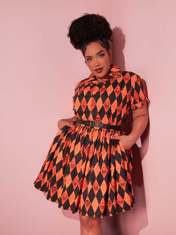 Model with her hands tucked into the pockets of her matching skirt that she's wearing with the all-new TRICK R TREAT™ Button Up Shirt in Halloween Harlequin Print.