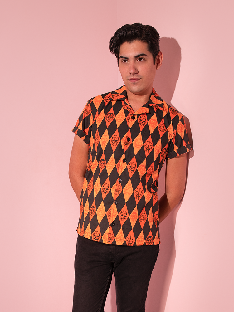Male model posing with his hands behind his back wearing the TRICK R TREAT™ Button Up Shirt in Halloween Harlequin Print.