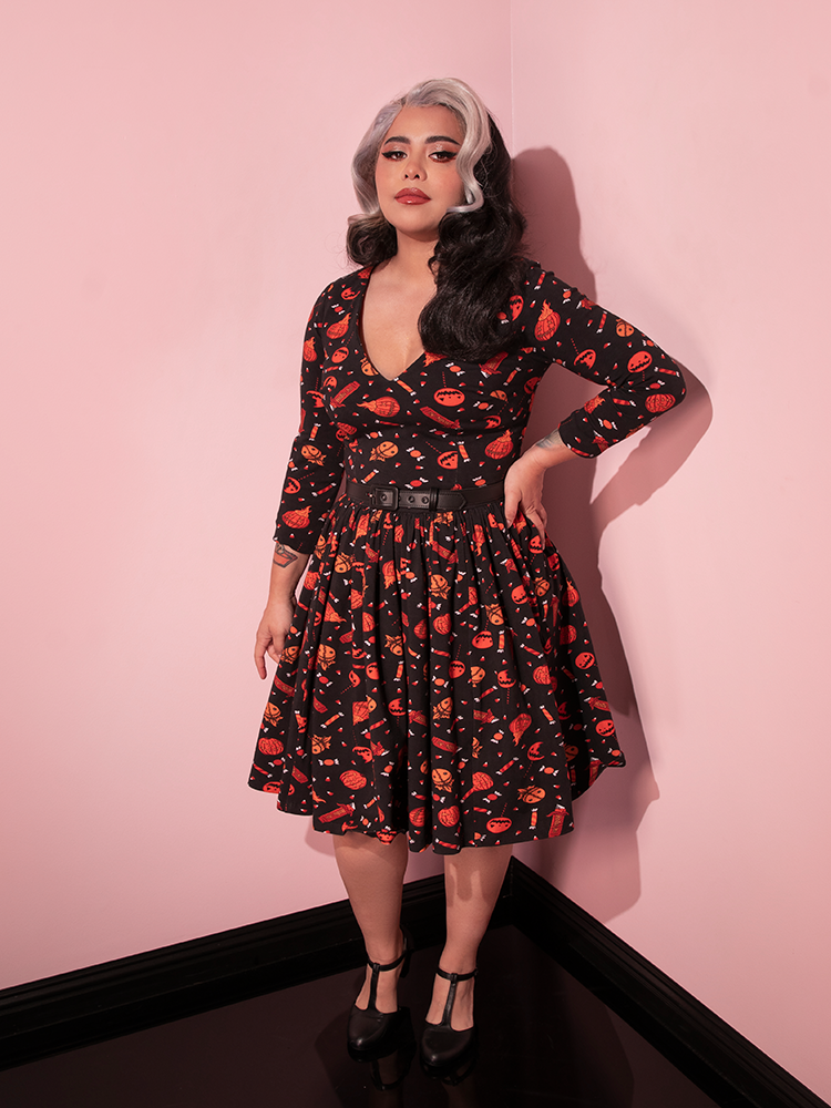 Model posing with hand on her hip while wearing the TRICK R TREAT™ Deadly Swing Dress in Candy Corn Novelty Print.