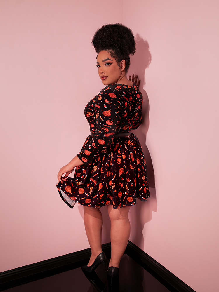 Model turned away from the camera to show off the back of the TRICK R TREAT™ Deadly Swing Dress in Candy Corn Novelty Print from Vixen Clothing.