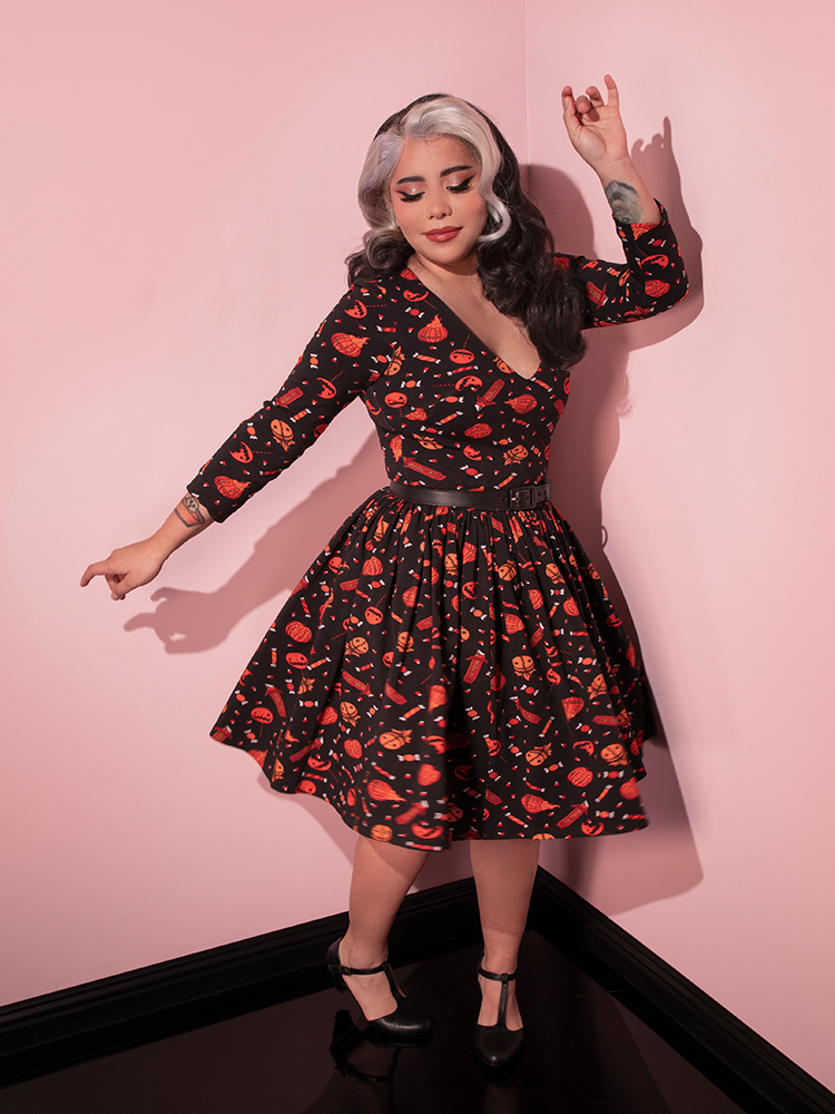 Model strikes a pose dancing around in the TRICK R TREAT™ Deadly Swing Dress in Candy Corn Novelty Print from retro clothing brand Vixen Clothing.