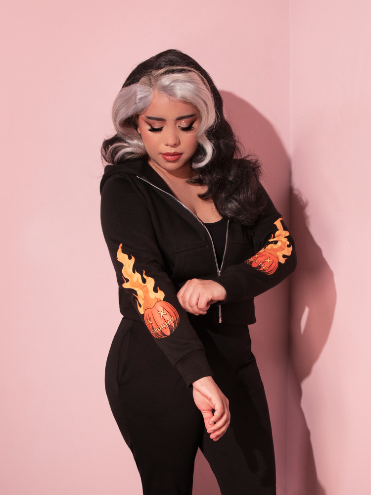 Model pulling on the sleeve of the TRICK R TREAT™ Sam Cropped Hoodie to show off the original art design emblazoned.