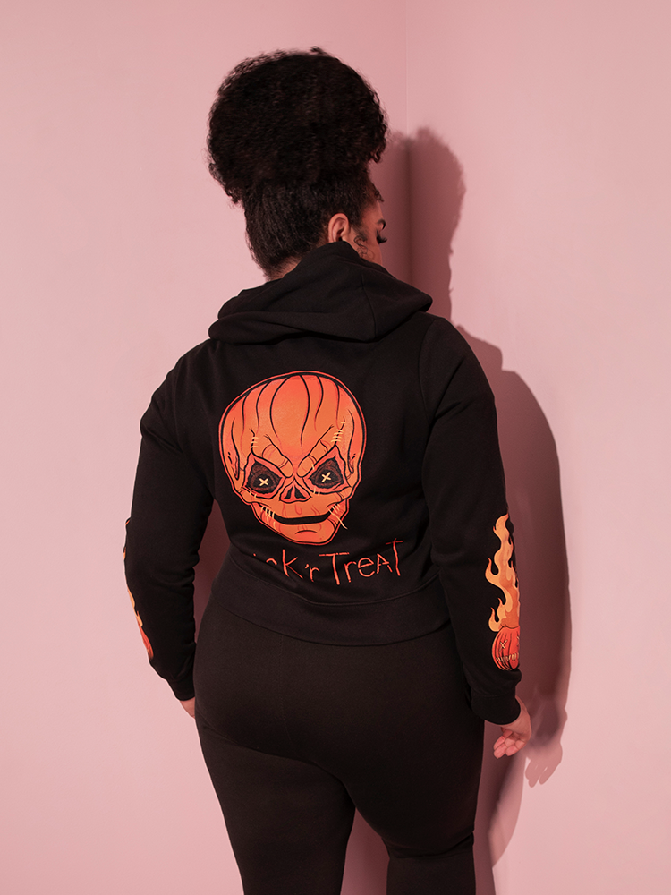 Female model posing in the TRICK R TREAT™ Sam Cropped Hoodie while also wearing black sweatpants. 