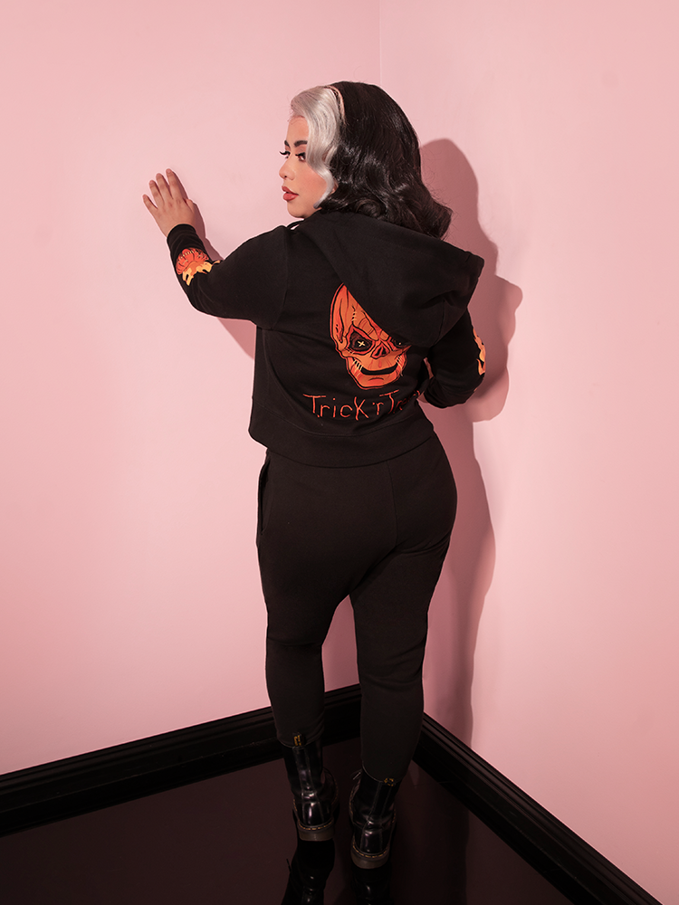 Model facing away from the camera to show off the back of the TRICK R TREAT™ Jack O' Lantern Sweatpants.