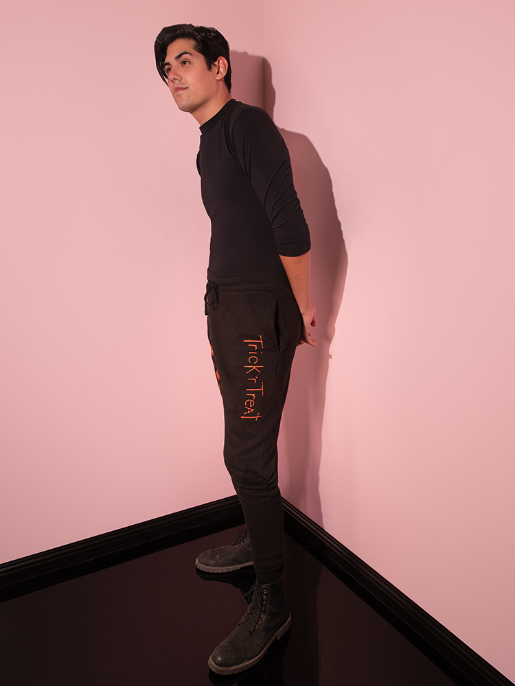 Profile shot of male model wearing the TRICK R TREAT™ Jack O' Lantern Sweatpants.