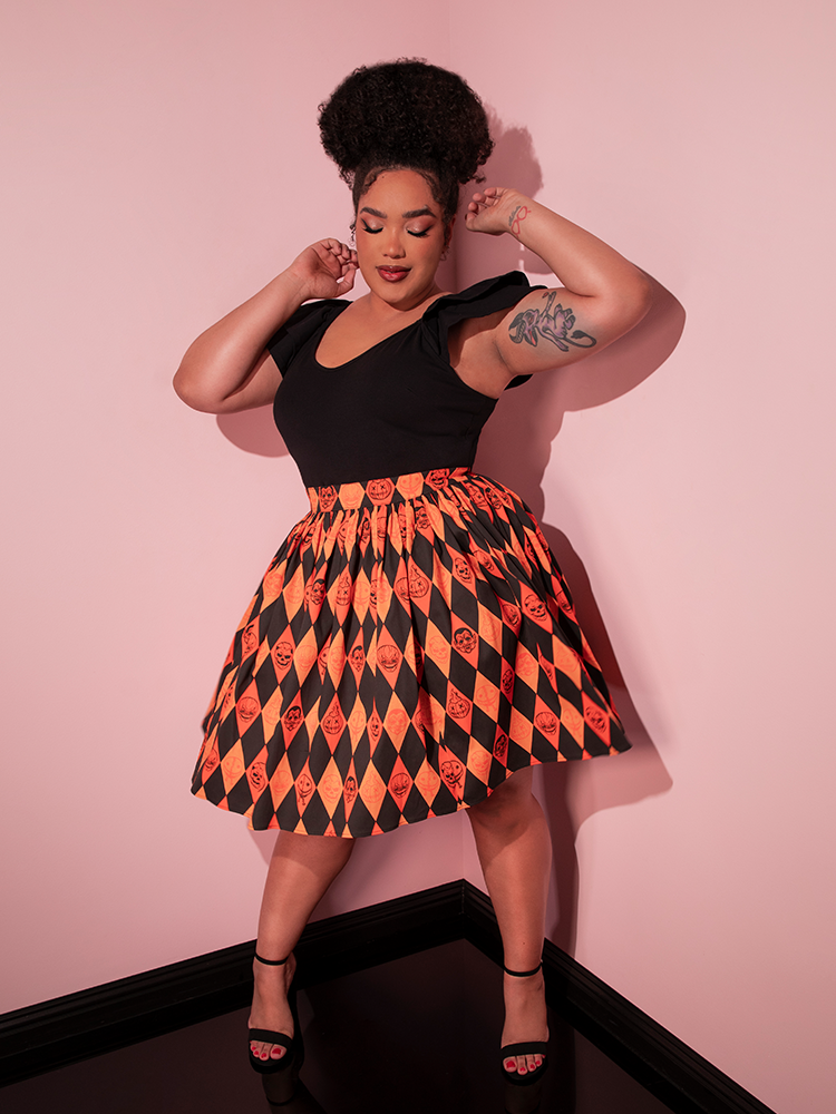 Model dancing around in the TRICK R TREAT™ Skater Skirt in Halloween Harlequin Print she's wearing with a tucked in black retro top.
