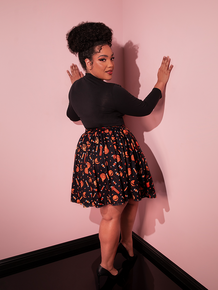 Female model facing away from the camera to show off the back of the TRICK R TREAT™ Skater Skirt in Candy Corn Novelty Print.