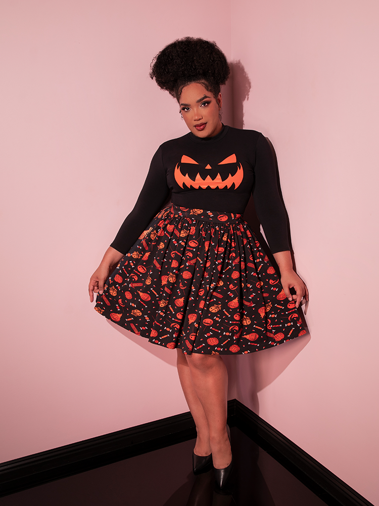 Model gently tugs out on the sides of the TRICK R TREAT™ Skater Skirt in Candy Corn Novelty Print to show off the festive Halloween print.