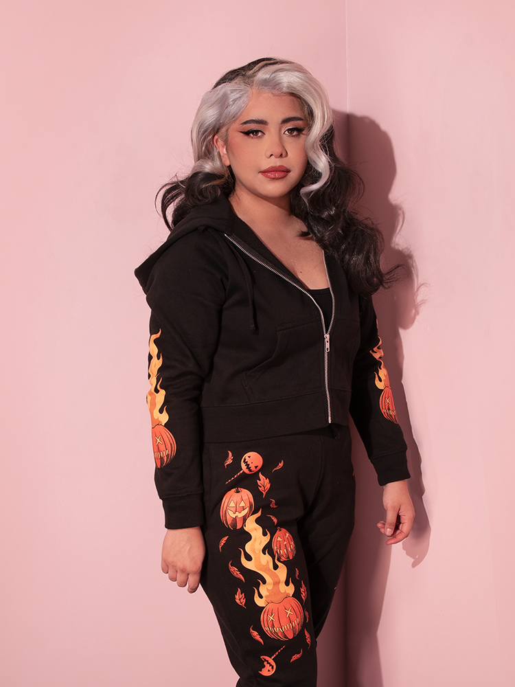 Model turned to the side shows off the flaming skull print on the sleeve of her TRICK R TREAT™ Sam Cropped Hoodie.
