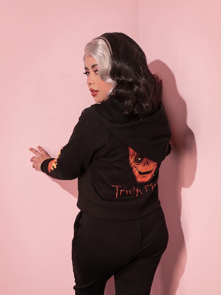 The back of the TRICK R TREAT™ Sam Cropped Hoodie being worn with black sweatpants.