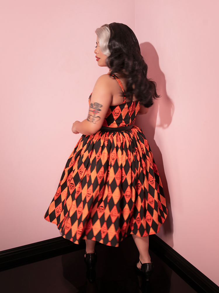 Model facing away from the camera to show off the back of the TRICK R TREAT™ Sweetheart Swing Dress in Halloween Harlequin Print. 