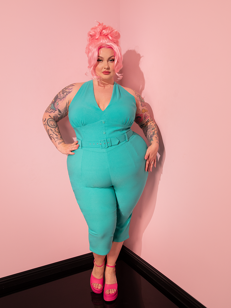 With grace and poise, a stunning vintage-style model models the Turquoise Capri Pants from Vixen Clothing, channeling the essence of retro fashion.