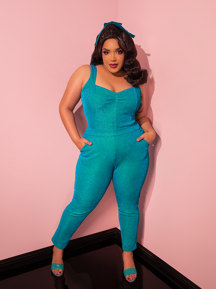 Mesmerizing in her retro attire, the gorgeous model strikes a fun and sexy pose, drawing attention to the Turquoise Lurex Cigarette Pants by Vixen Clothing.