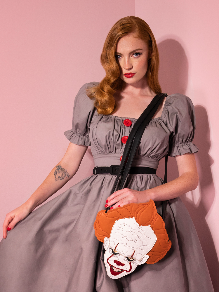Model Emily shows off her dress and Pennywise clown crossbody bag by Vixen Clothing.