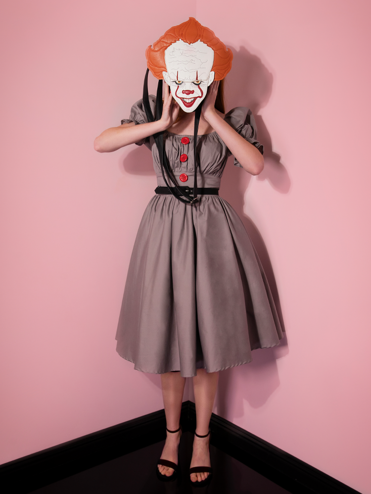 Holding a Pennywise bag in front of her face, Emily models the Pennywise babydoll dress from Vixen Clothing.
