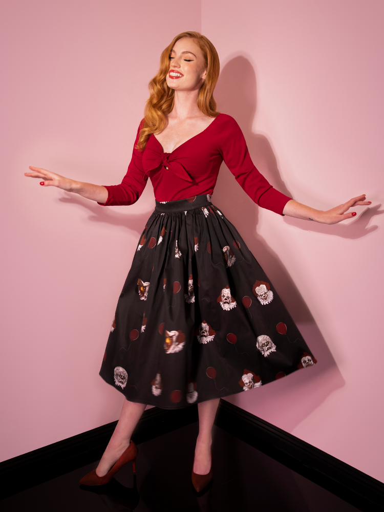 With a smile on her face while twirling, Emily shows off the Pennywise swing skirt in black by Vixen Clothing.